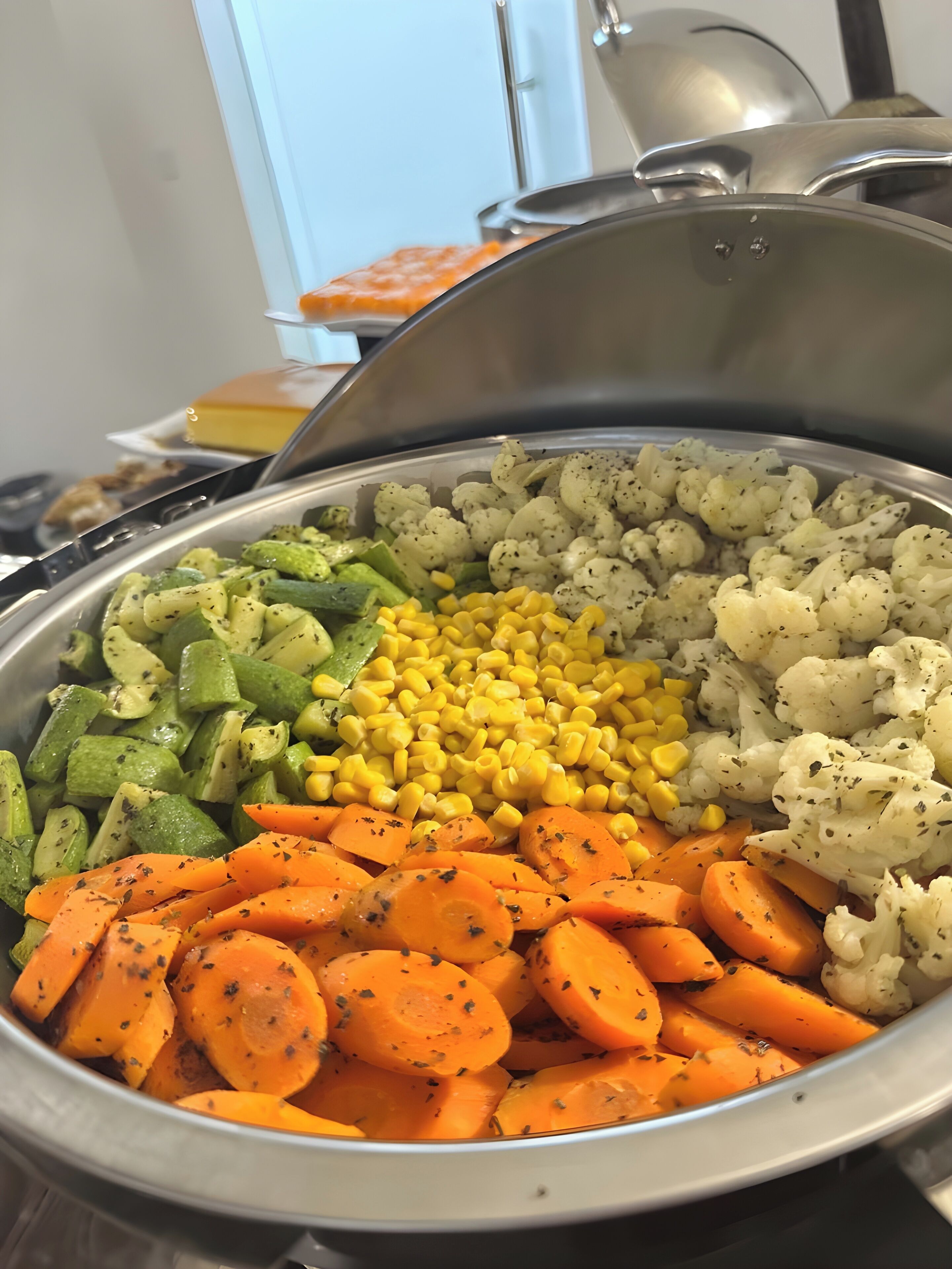 A buffet with various vegetables including carrots, cauliflower, and corn.