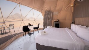 Een ingerichte tent met een bed, een bureau en een stoel.
