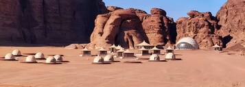 Paisaje desértico con formaciones rocosas y varias estructuras en forma de cúpula.