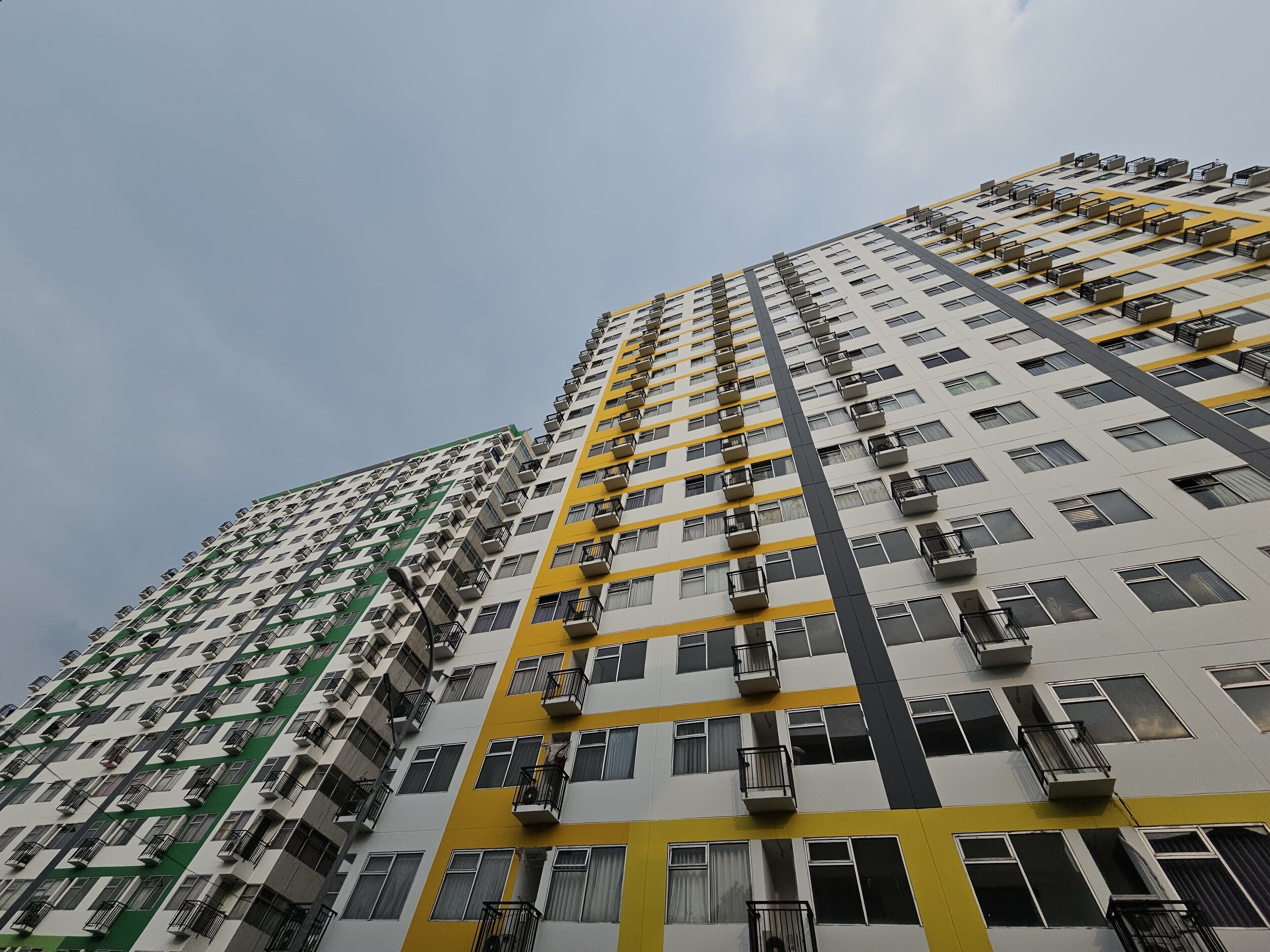 Un edificio alto con varios balcones y unidades de aire acondicionado.