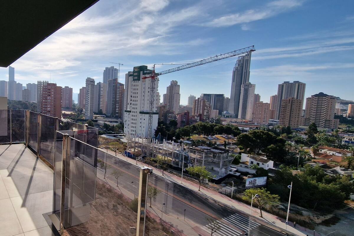 A balcony with a city view, including high-rise buildings and a construction crane.