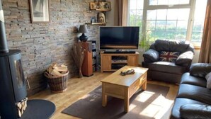 Ein gemütliches Wohnzimmer mit Kamin, Fernseher, Sofa und Couchtisch.