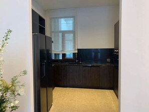 A compact kitchen with dark cabinetry, a black refrigerator, and a window above the sink.
