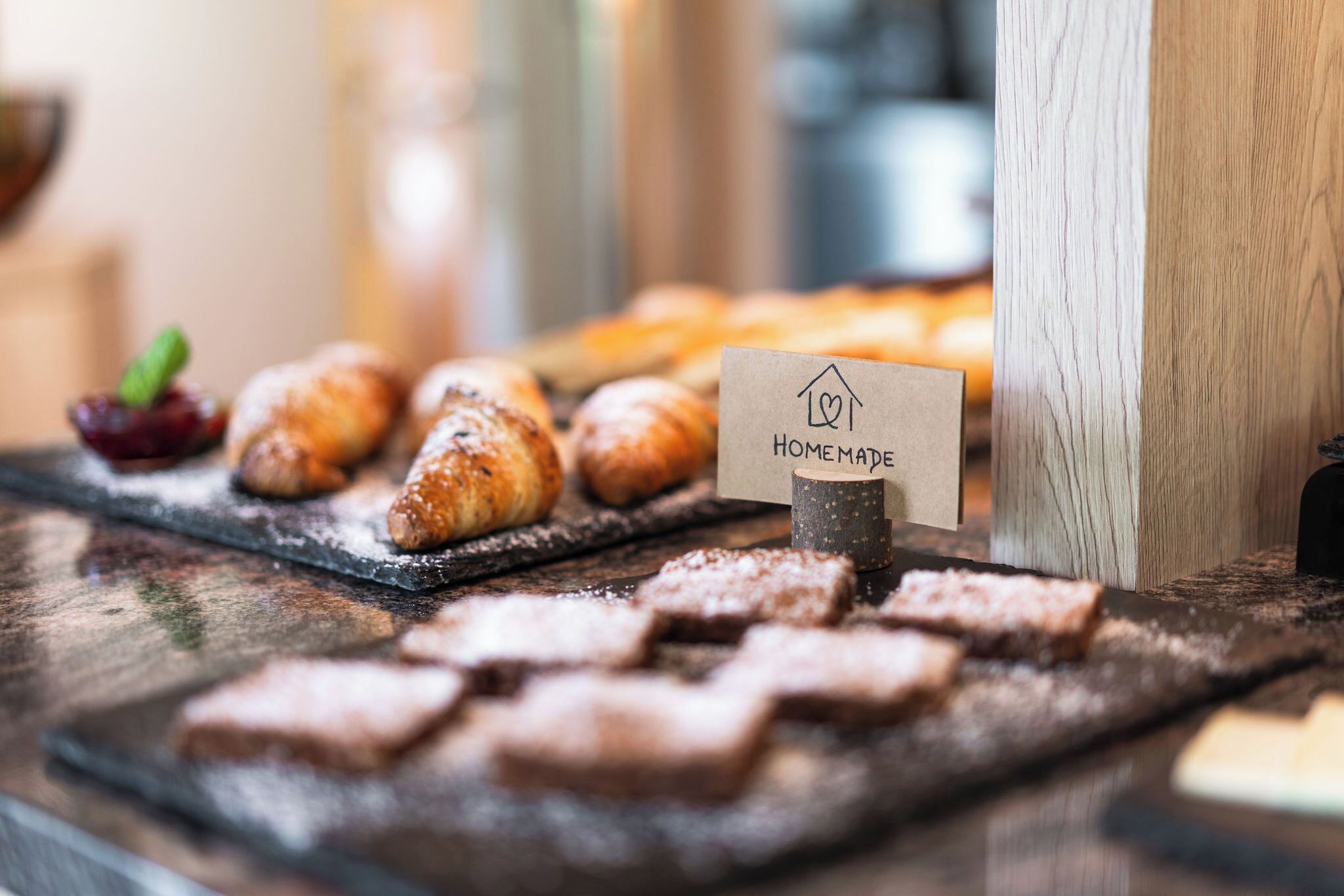 A wooden table with pastries and a sign that reads 'HOME MADE.'