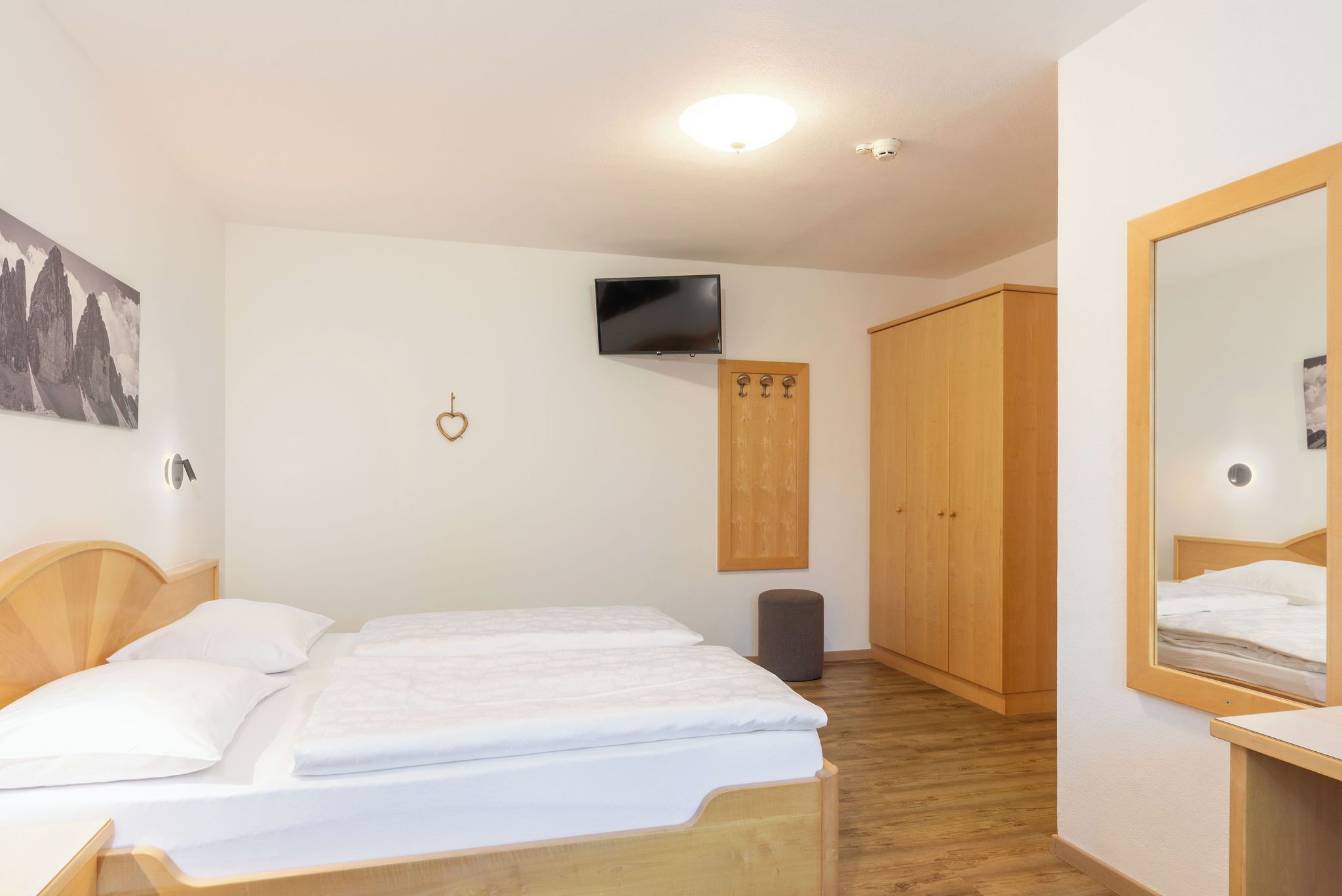 Un dormitorio con cama, televisión, armario y espejo.