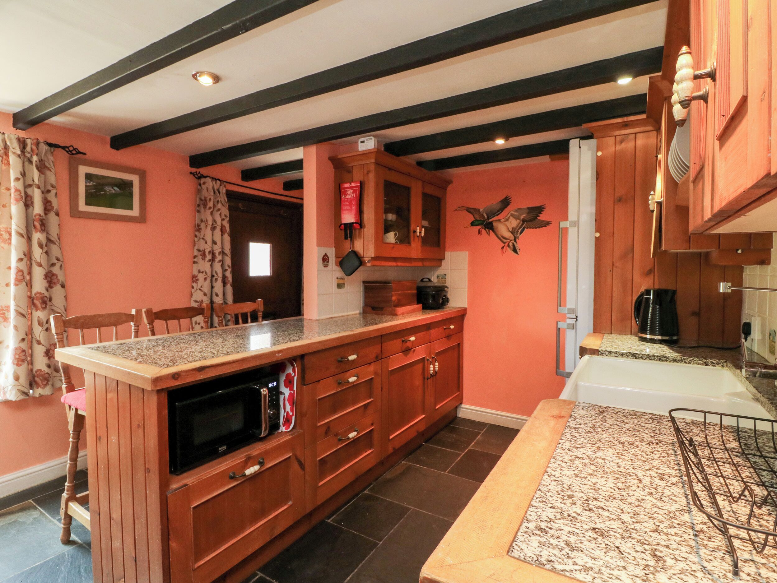 A kitchen with wooden cabinets, a granite countertop, a microwave, and a coffee maker.