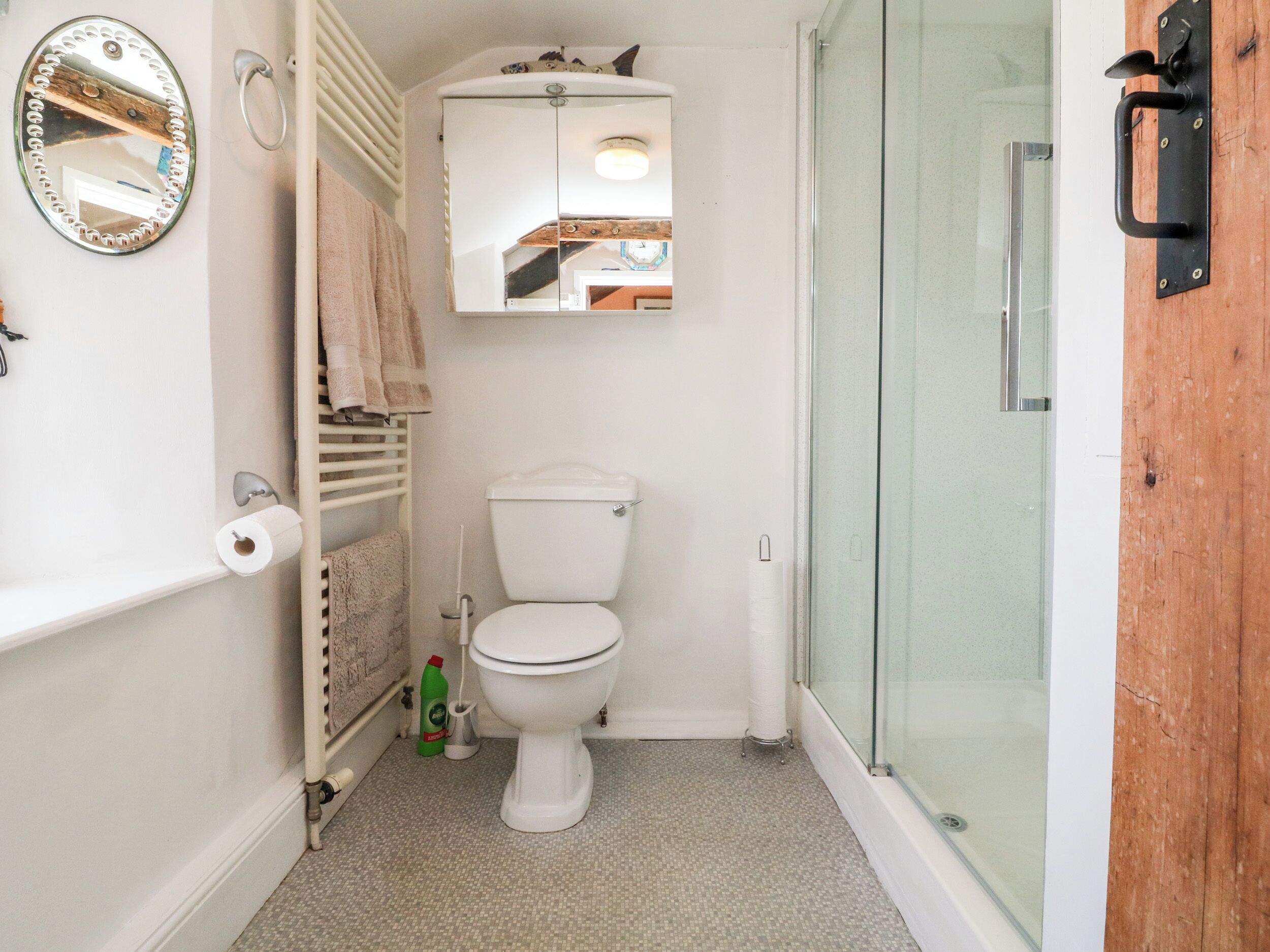 Une petite salle de bain comprenant des toilettes, une douche à parois de verre, un miroir et un porte-serviettes.