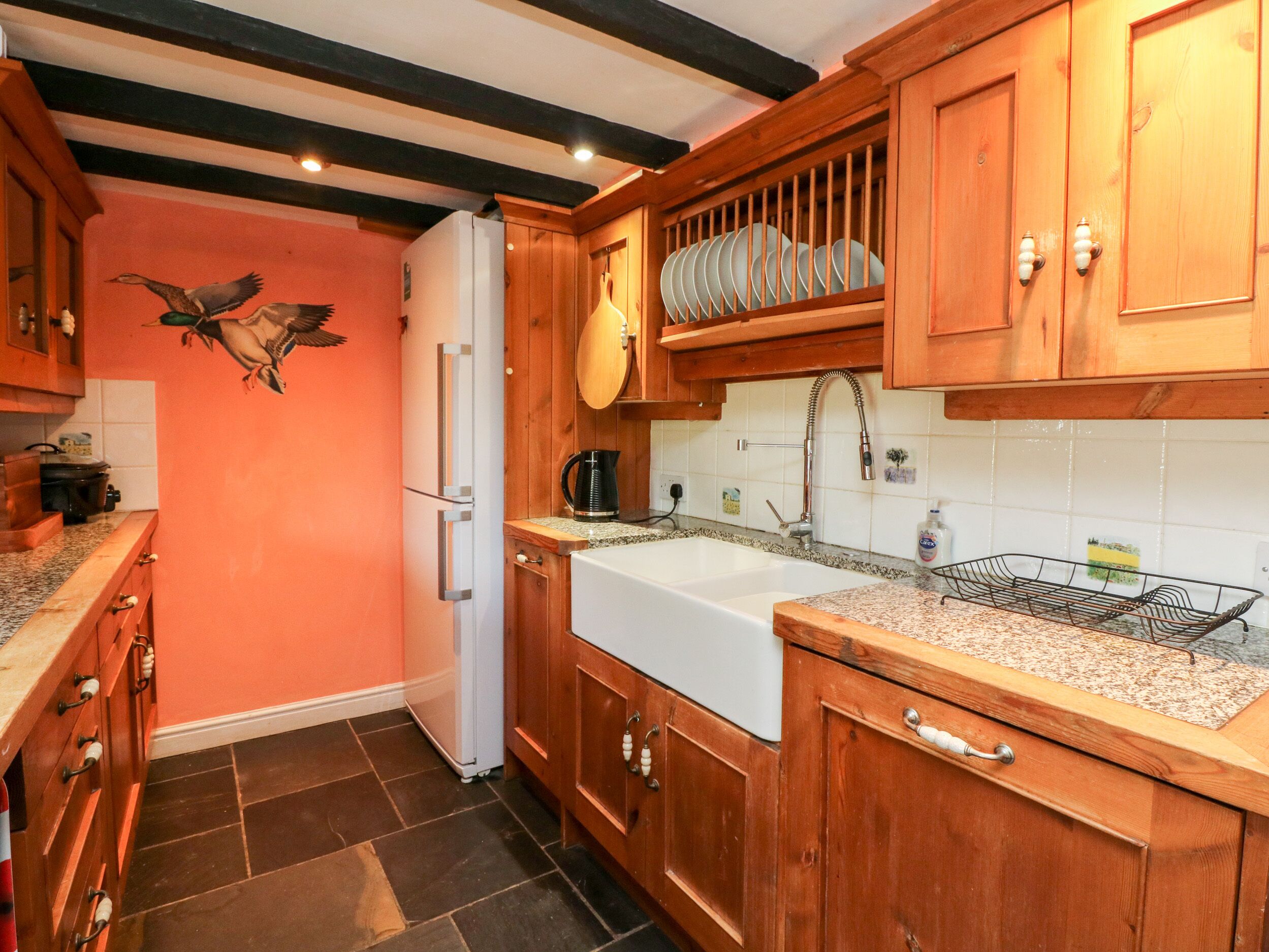 A kitchen with wooden cabinets, a white refrigerator, and a tiled backsplash.