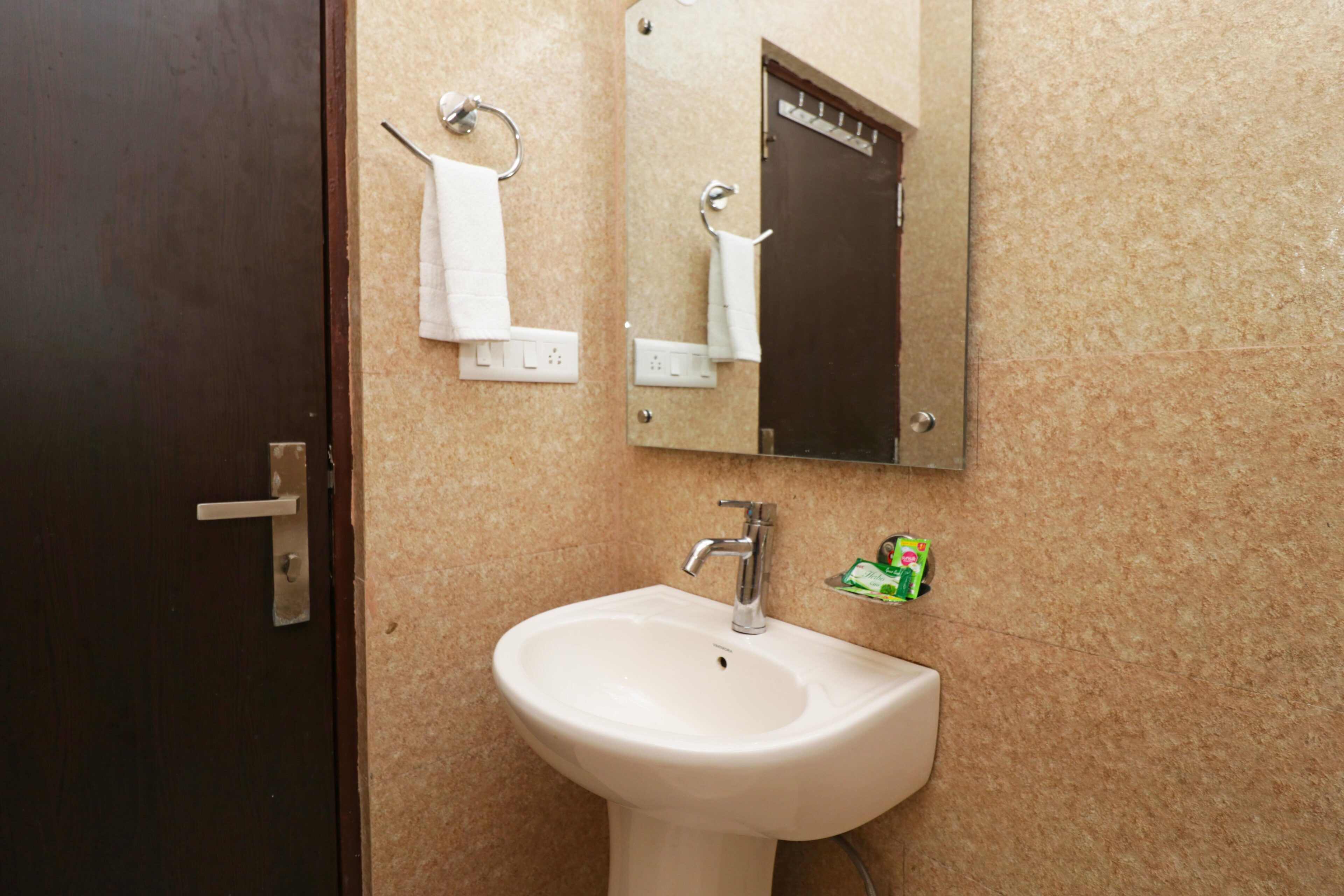 Un baño con lavamanos, toallero y espejo.