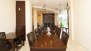 Una larga mesa de comedor con sillas, luces colgantes y un adorno central.