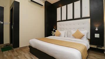 Habitación de hotel con una cama grande, cabecera con paneles, un tapete verde y un equipo de aire acondicionado.