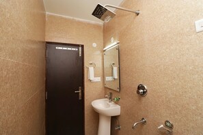 A bathroom with a dark door, a white sink, a mirror, and a showerhead. - Hotel Mirage Residency (Dharamshala)