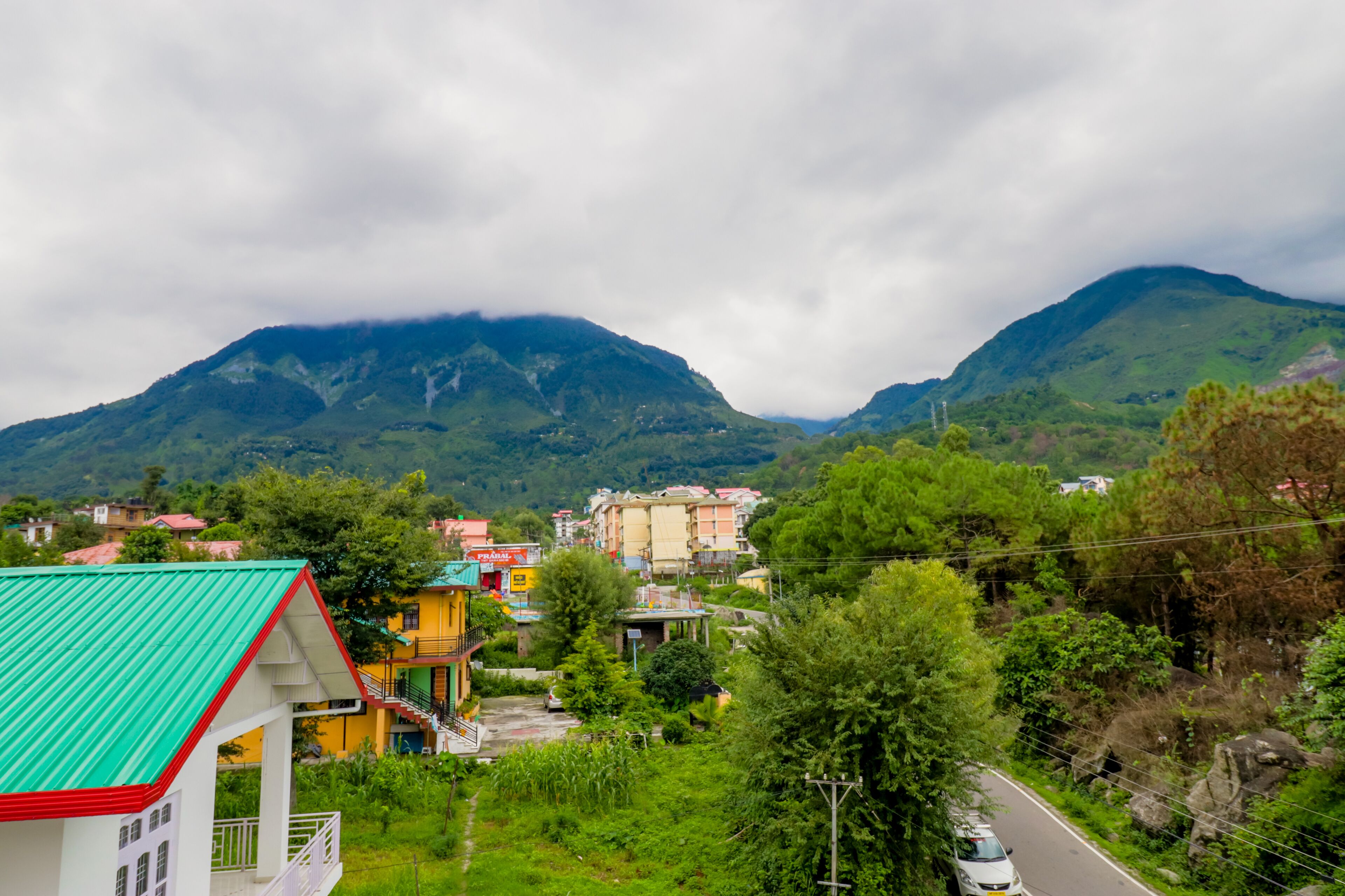 A residential area with houses, a road, and mountains in the background.
