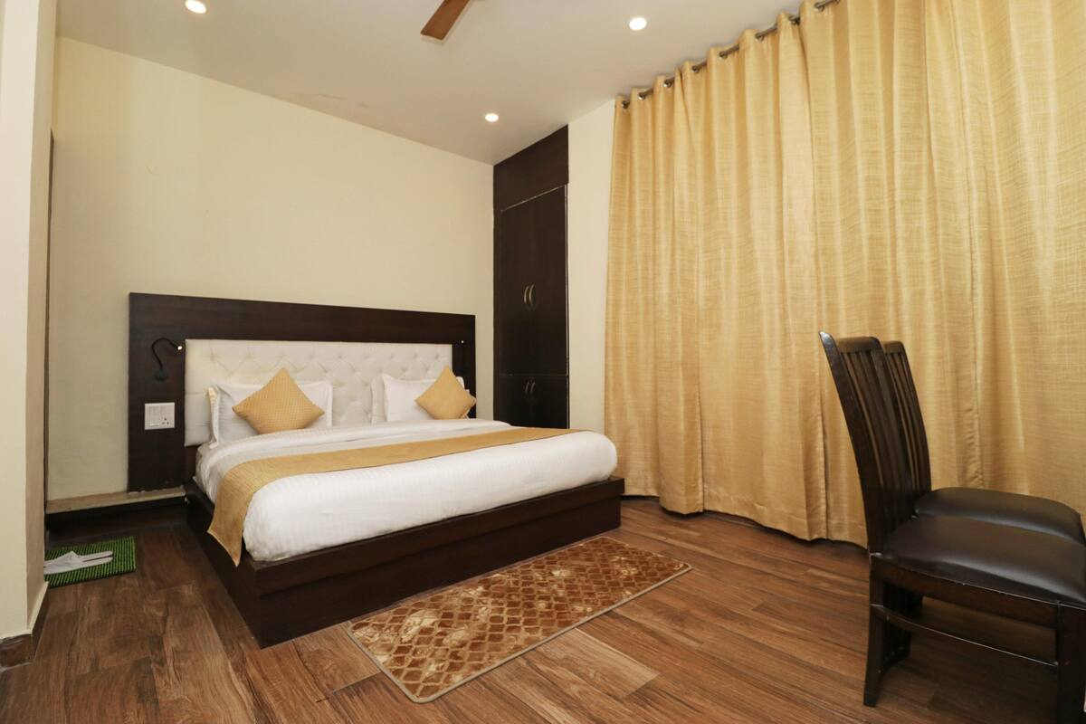 Un dormitorio con una cama grande, piso de madera, una silla y un armario.