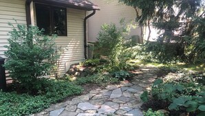 Un chemin de pierres qui mène à une maison avec une fenêtre et une porte.