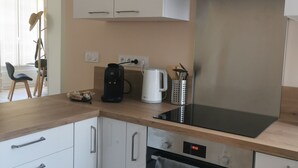Une cuisine moderne avec des meubles blancs, un four Bosch, une machine à café et une bouilloire.