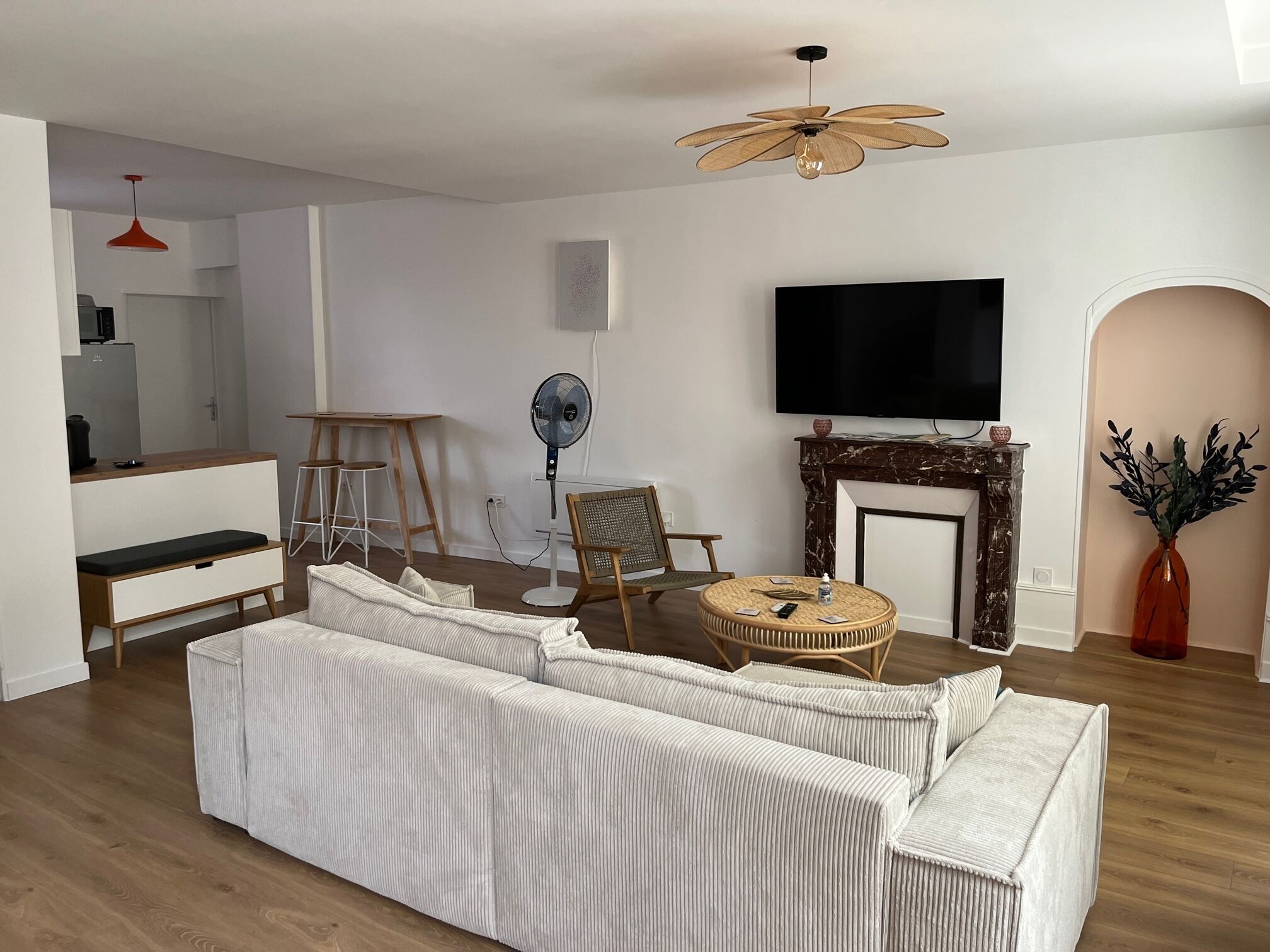 Ein Wohnzimmer mit einem großzügigen Ecksofa, einem Flachbildfernseher, einem Kamin und einem Essbereich mit einem Holztisch und Stühlen.