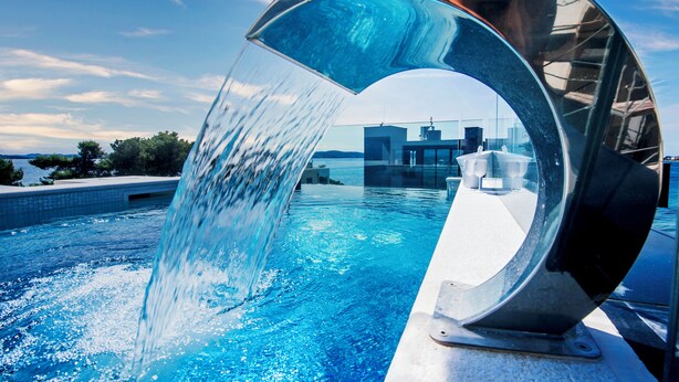 A modern pool with a unique water feature and a clear view of the surrounding landscape.