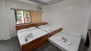 A hotel room with two single beds, a wooden headboard, a window with a view of the outdoors, and an air conditioning unit on the wall. - MGG Casa Dela Playa (Boracay Island)