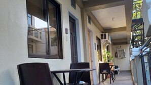 A corridor with a dining area featuring tables and chairs, air conditioning units, and a door with a sign. - MGG Casa Dela Playa (Boracay Island)
