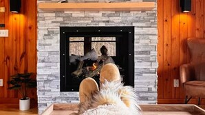 Una sala de estar acogedora con chimenea, paredes de madera, un sofá cómodo y un cuadro grande sobre la chimenea.