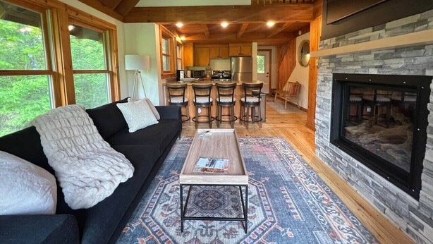 Una sala de estar acogedora con un sofá negro, una mesa de centro y una chimenea.