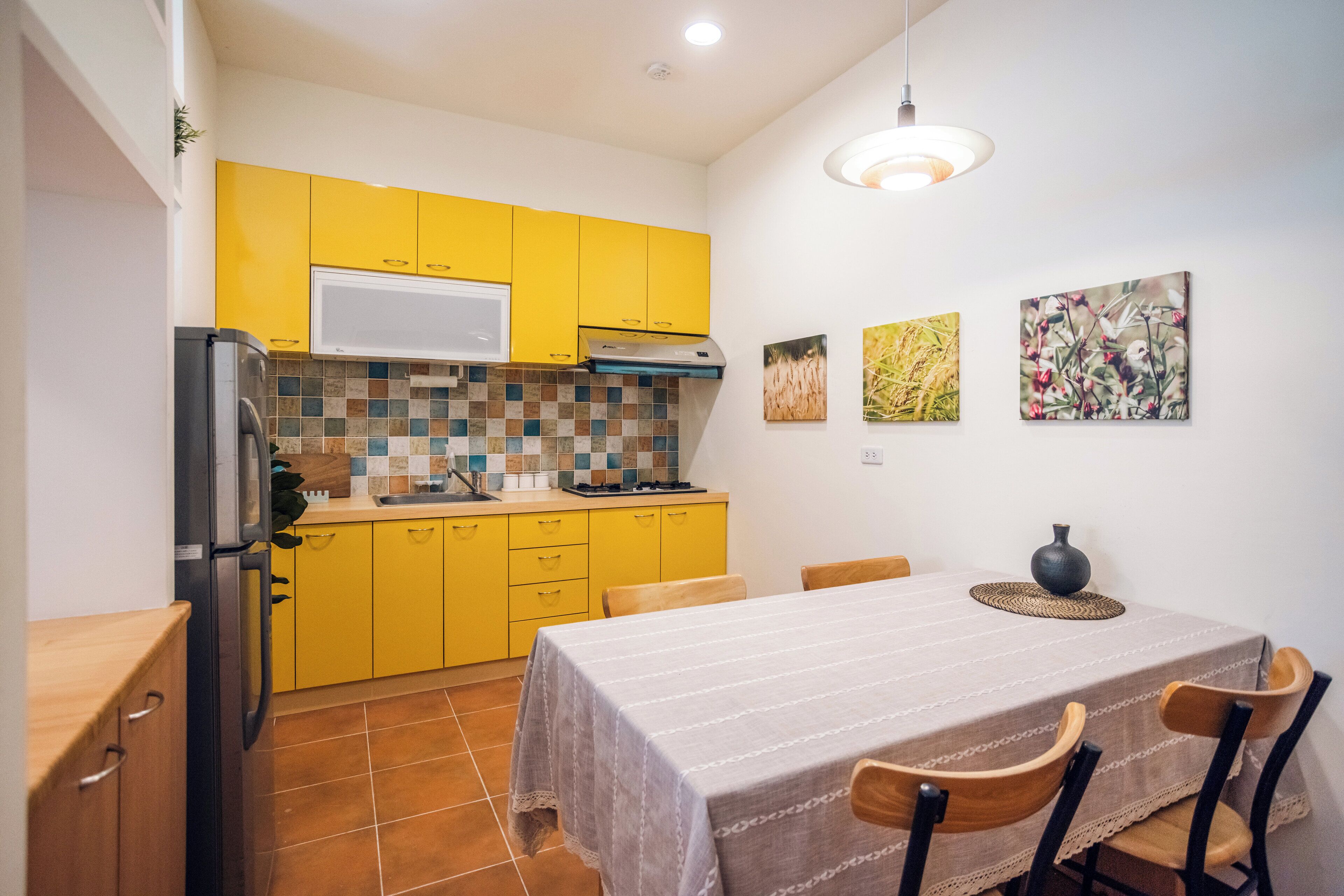 A compact kitchen with yellow cabinets, a tiled backsplash, and a dining area with a table and chairs.