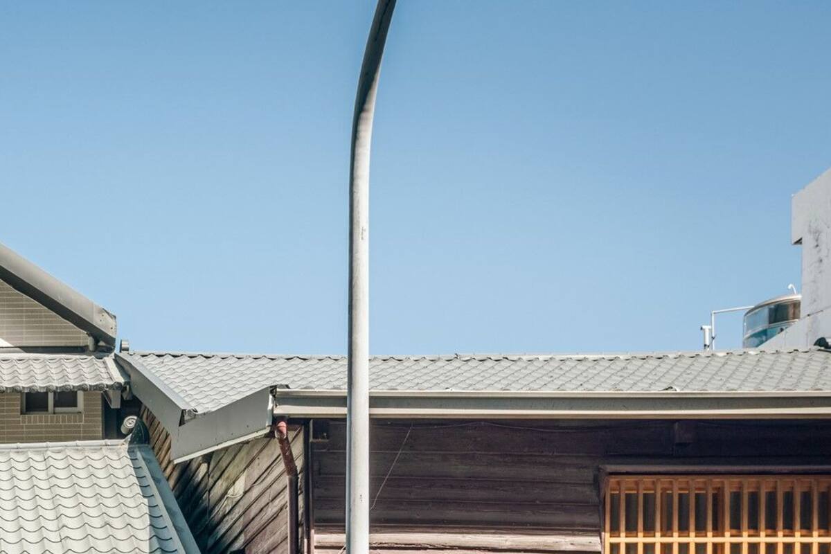 A traditional Japanese house with a sloped roof, a small window, and a tiled exterior.