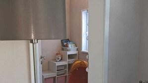 A narrow hallway with a patterned rug, a red bucket, and a white shelf with books and a small container. - Double vacation bungalow in the middle of the Schorfheide (Joachimsthal)