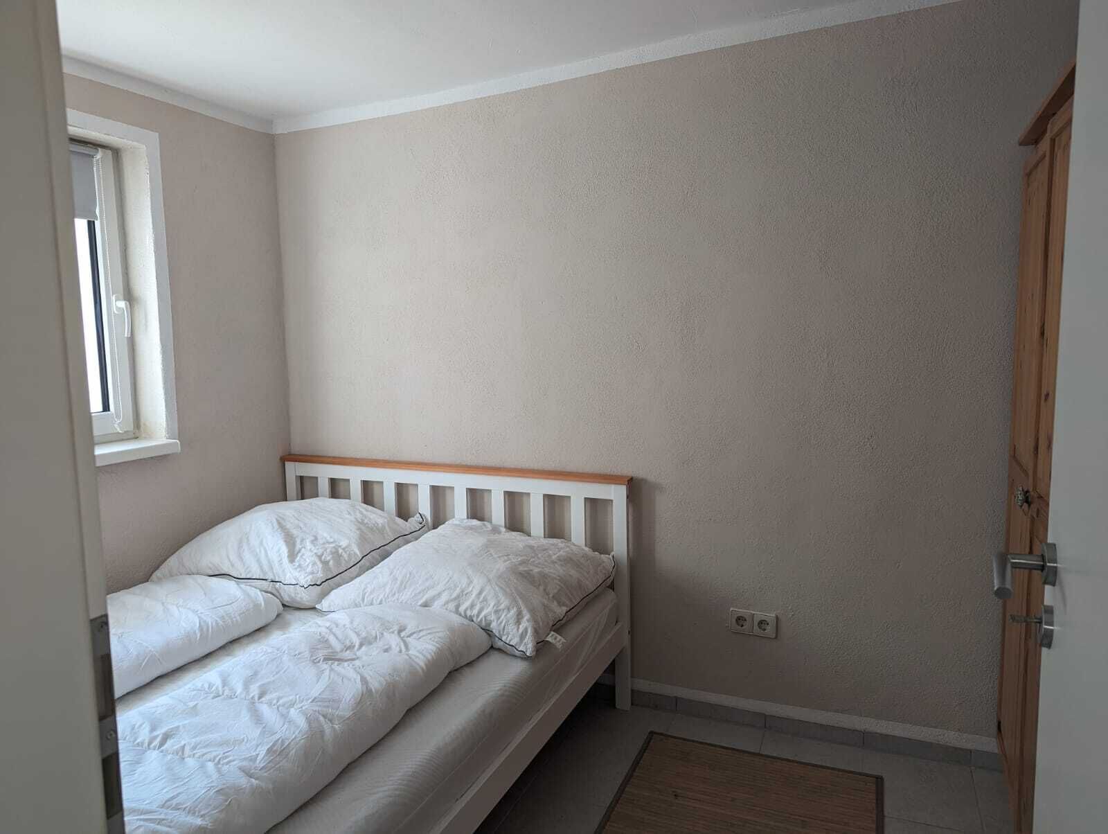 Un dormitorio con una cama individual, una ventana y una puerta.