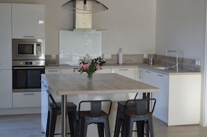 A modern kitchen with a central island, stainless steel appliances, and bar stools.