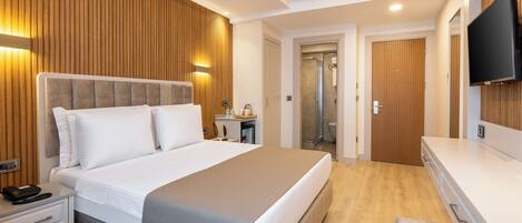 A modern hotel room with a large bed, bedside table, and a TV mounted on the wall.