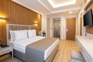 A modern hotel room with a large bed, bedside table, and a TV mounted on the wall.