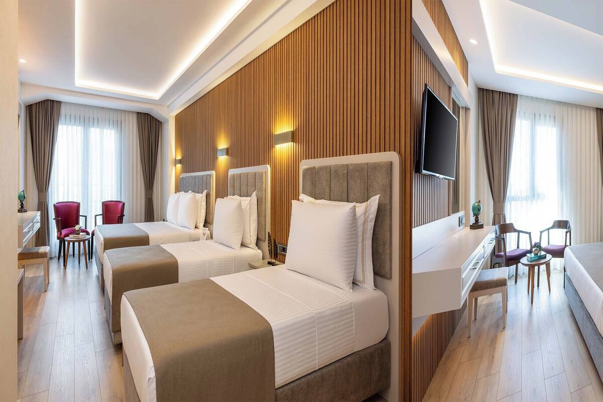 Hotellihuone, jossa on kaksi sänkyä, työpöytä, televisio ja oleskelualue tuoleineen.