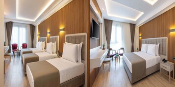 Een hotelkamer met twee bedden, een bureau, een televisie en een zithoek met stoelen.