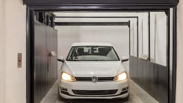 A white car inside an elevator with metallic walls and a control panel on the left.