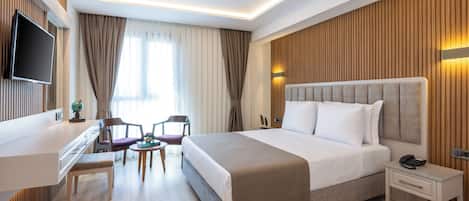 A modern hotel room with a large bed, bedside table, and a flat-screen TV mounted on the wall.