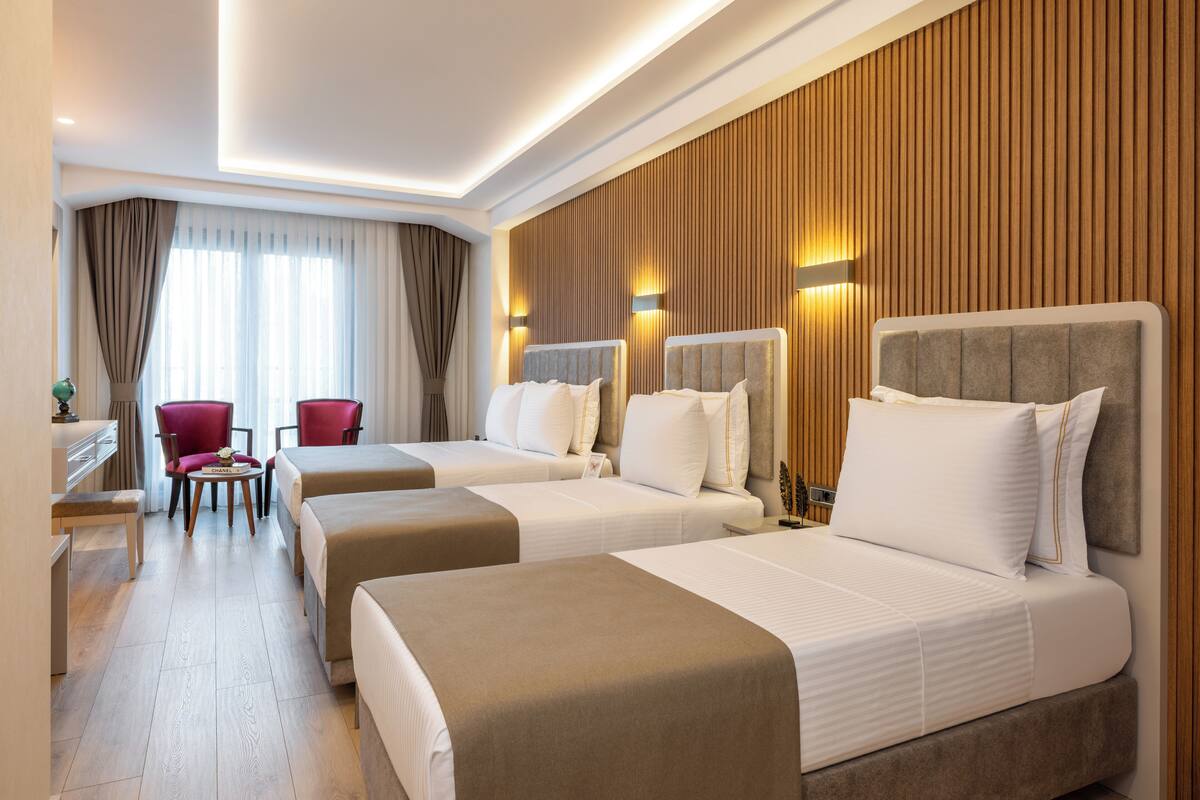 Hotellihuone, jossa on kaksi sänkyä, työpöytä ja tuoli.