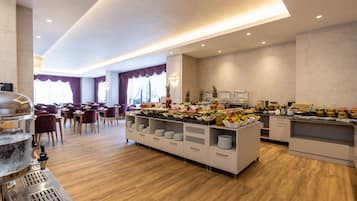 A buffet area with a variety of food items, a coffee machine, and a seating area with chairs and tables.