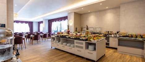 A buffet area with a variety of food items, a coffee machine, and a seating area with chairs and tables.