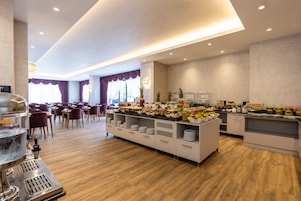 A buffet area with a variety of food items, a coffee machine, and a seating area with chairs and tables.