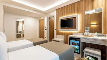 Habitación de hotel con dos camas, un minibar, televisión y un panel de pared de madera.