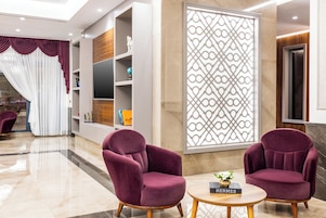 Un moderno vestíbulo con dos sillones mullidos, una mesa redonda con un libro y un separador decorativo.