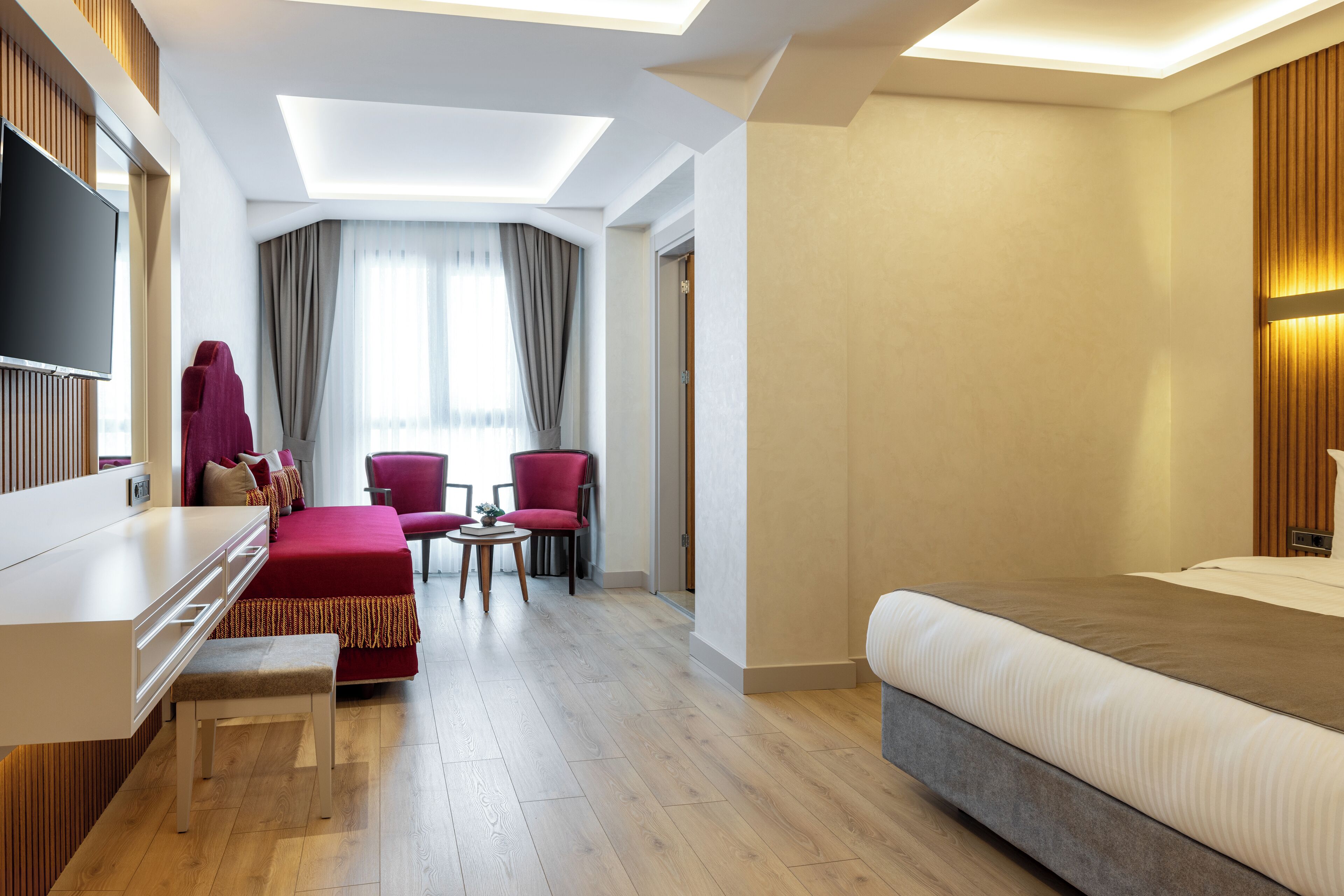 Una camera d'albergo moderna con un letto grande, una scrivania, una televisione e un'area salotto con due poltrone.