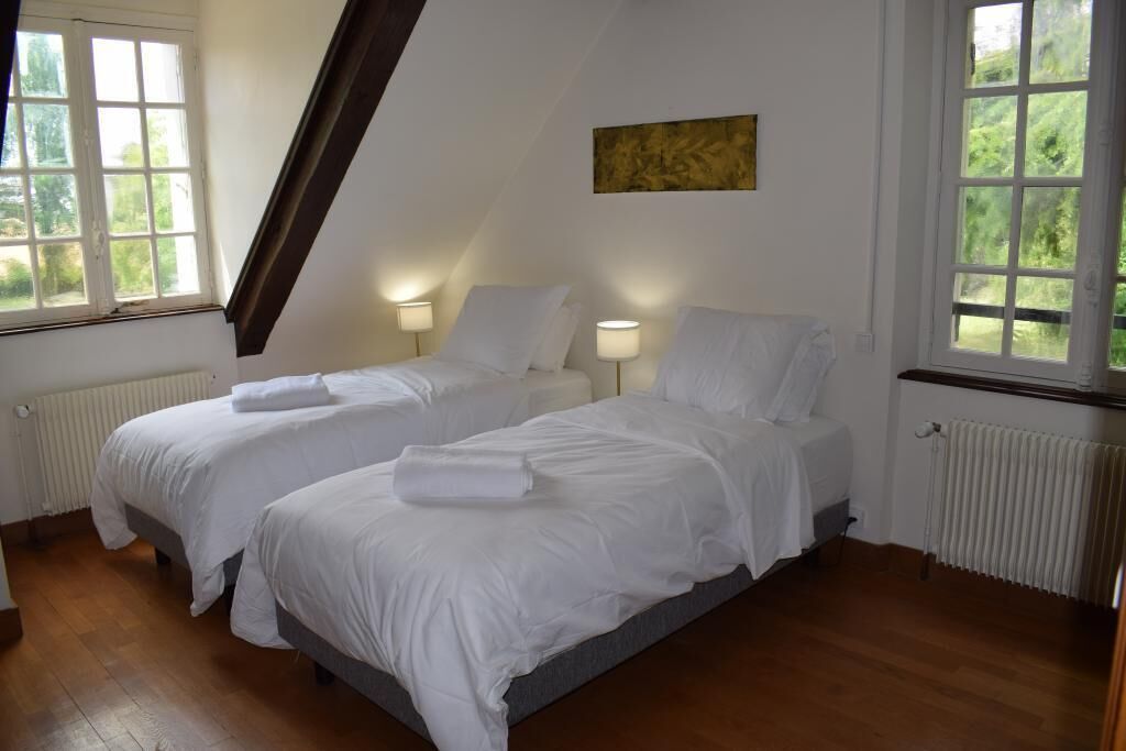 A bedroom with two beds, white linens, and bedside lamps.