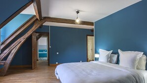 Un dormitorio con techo inclinado, una cama grande y piso de madera.
