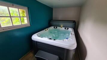 Une petite pièce avec un jacuzzi, une fenêtre et un banc.