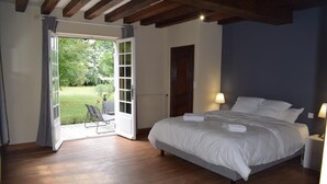 Un dormitorio con una cama grande, una puerta que da a un balcón y una silla afuera.