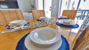 A dining table with blue placemats, white plates, and silverware arranged for a meal.