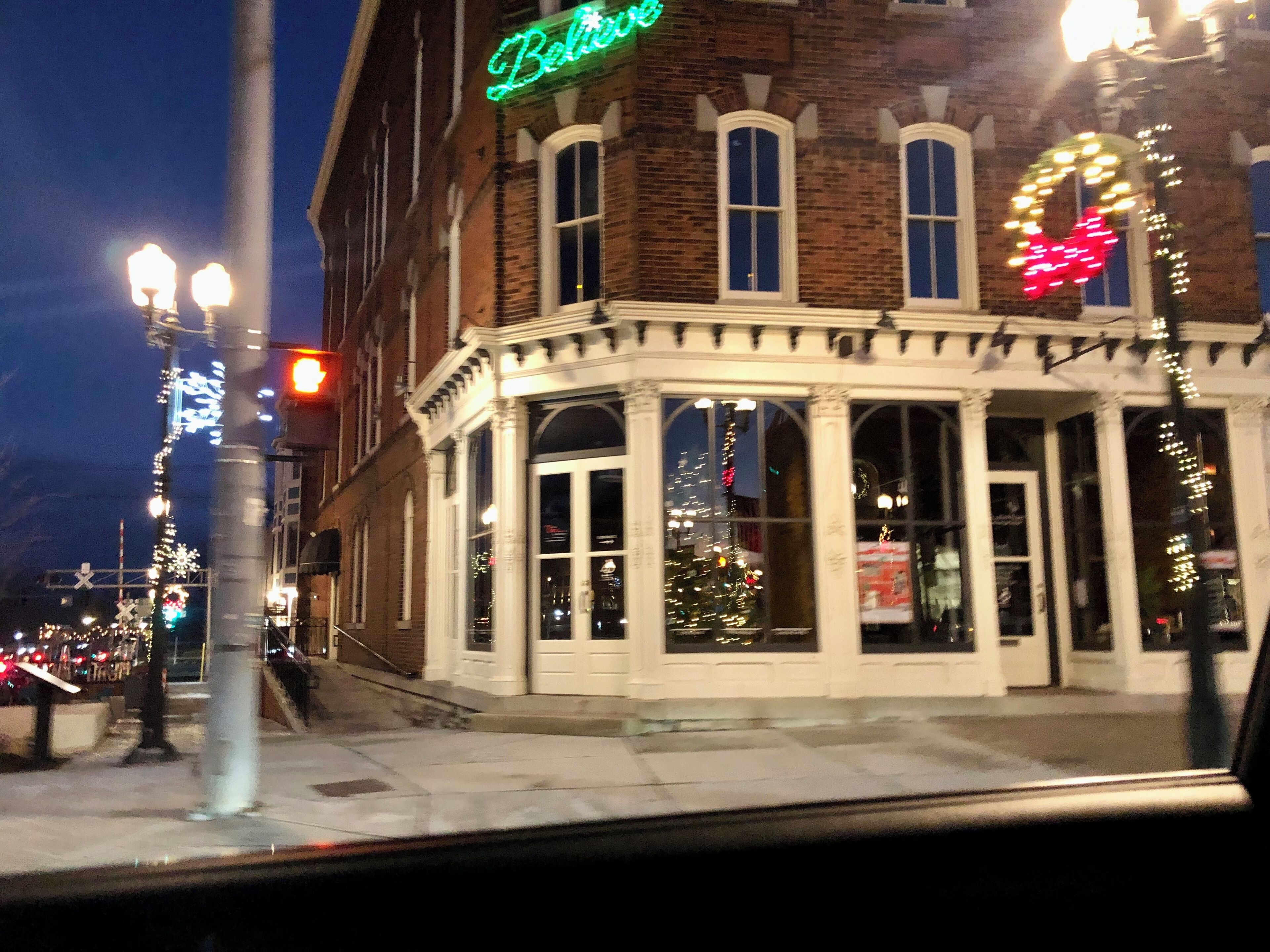 A corner building with a neon sign, large windows, and a brick facade.
